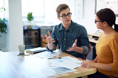 man and woman sitting at a desk, discussing business