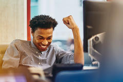 man cheering behind computer