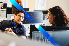 man and woman talking behind computer screen