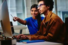 Woman pointing at the computer screen of her male colleague