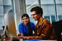 Photo of 2 people looking at a computer screen.
