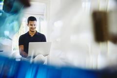 Smiling man working from home on laptop.