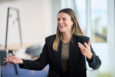 A woman looking next to the camera, laughing, gesticulating with her hands.