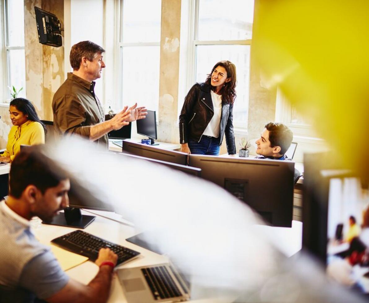Multiple people talking and laughing behind their desks.