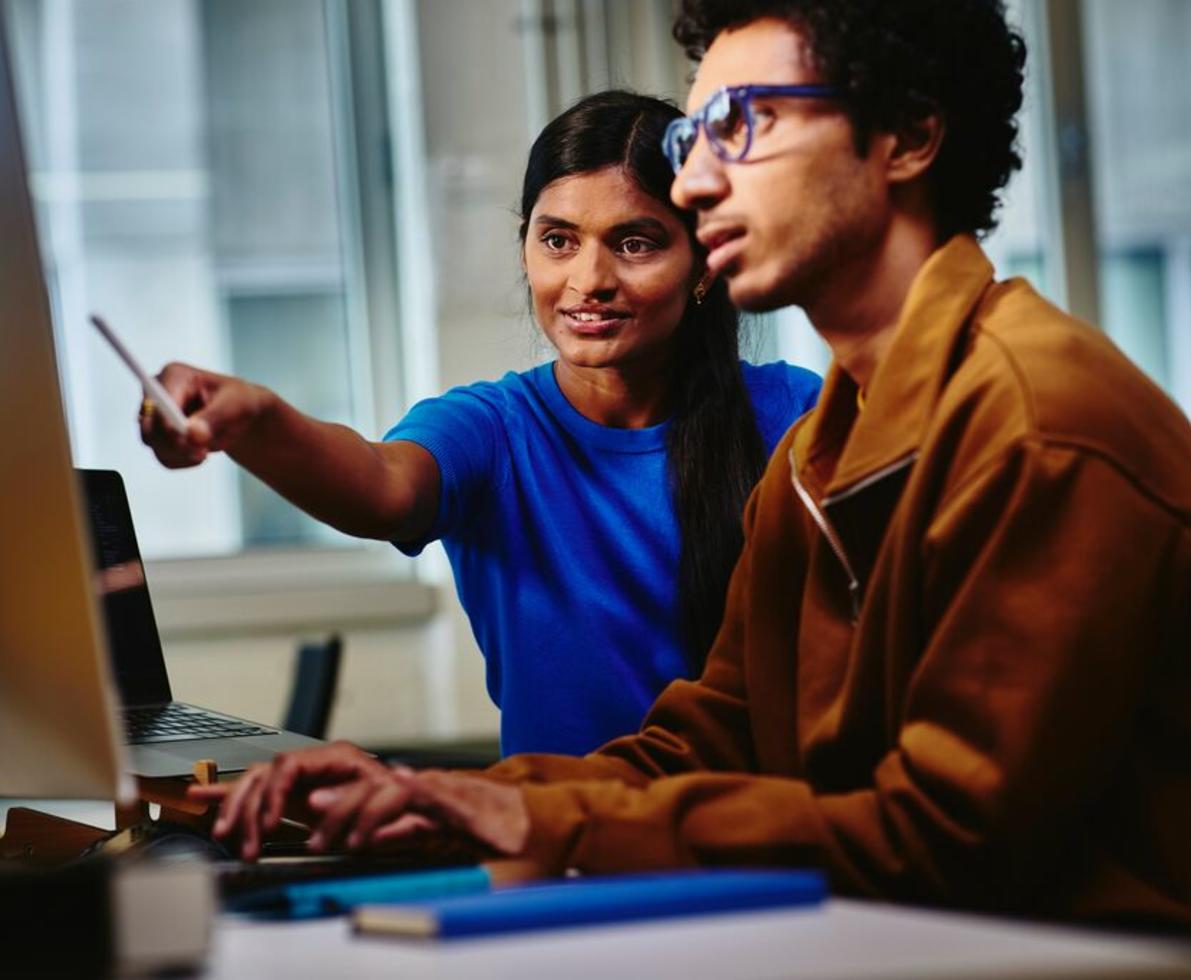 Woman pointing at the computer screen of her male colleague