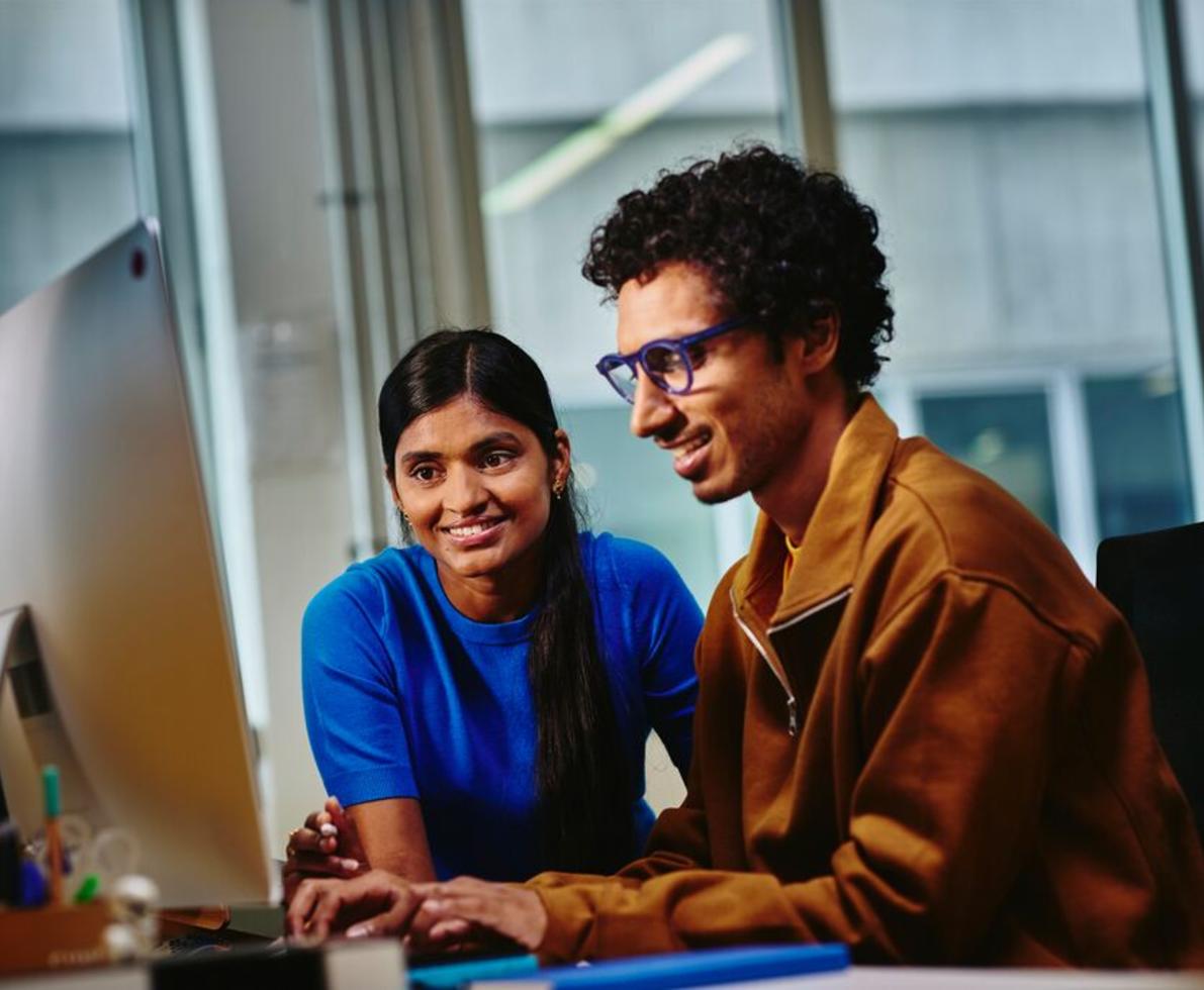 Photo of 2 people looking at a computer screen.