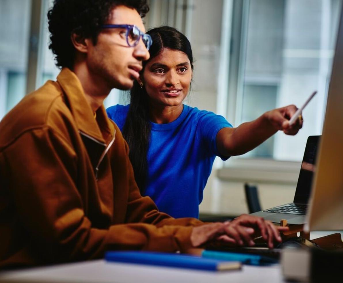 diverse coworker pointing to desktop screen
