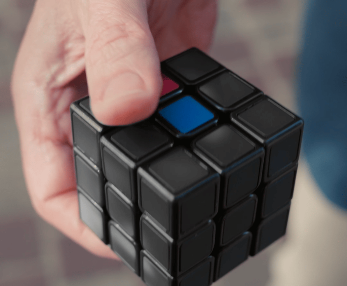 hand pressing a black cube 